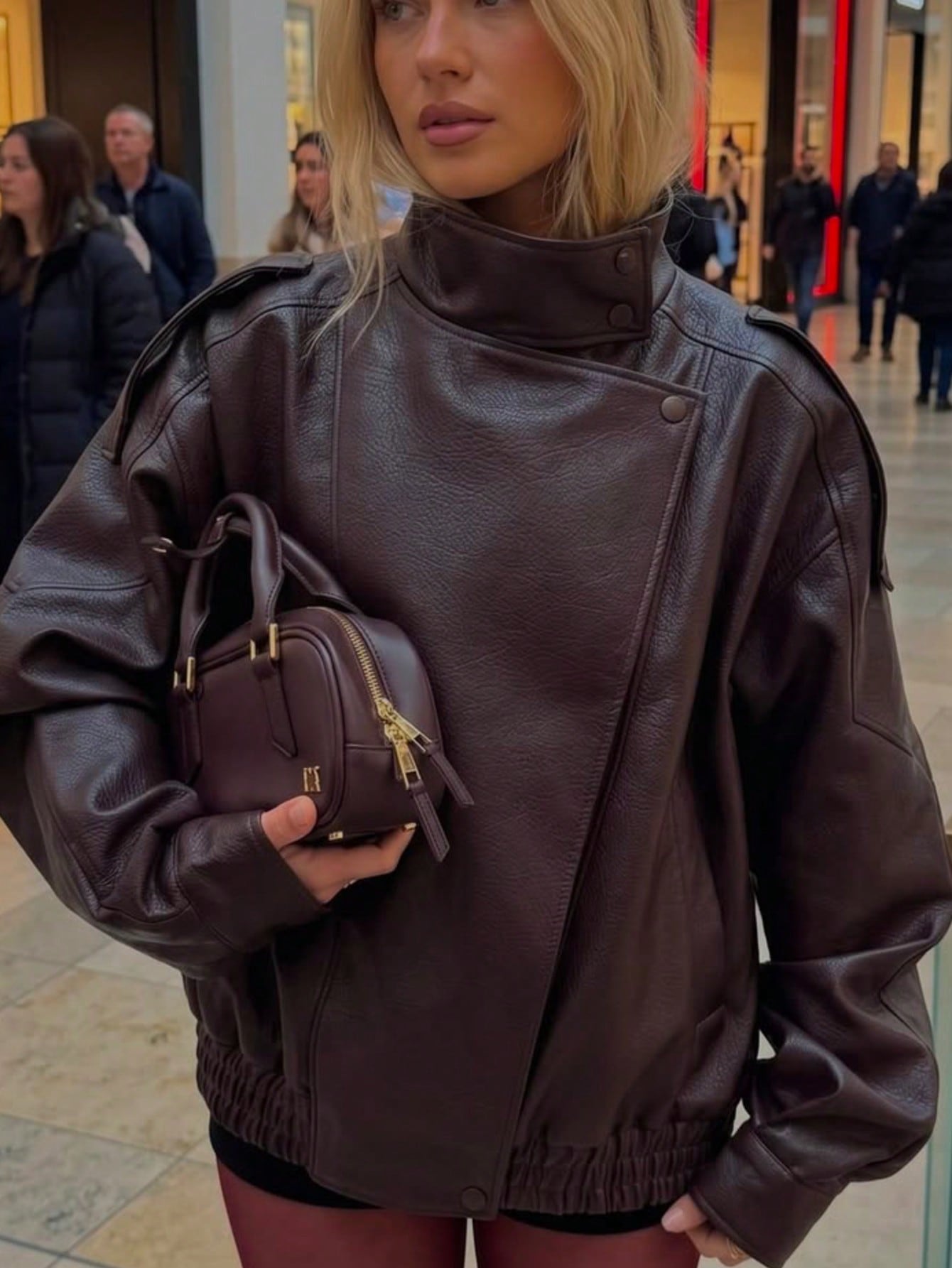 Mulher usando jaqueta feminina bomber oversized Camellia em couro sintético marrom